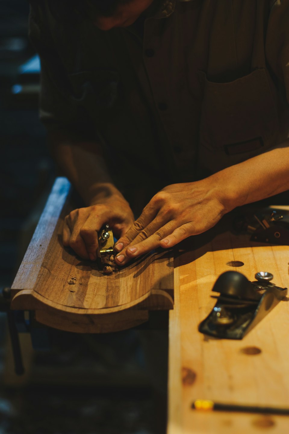 Mani di artigiano che modellano il legno con una pialla.