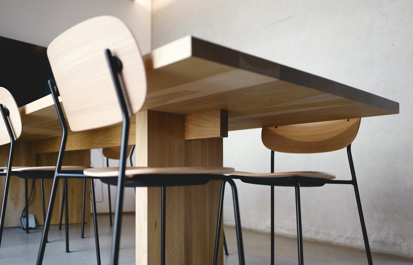 Tavolo e sedie moderni in legno con struttura in metallo nero.